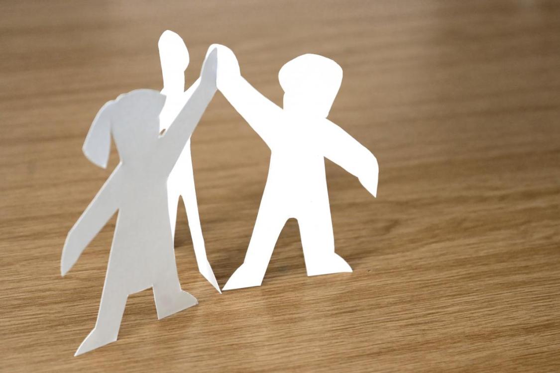 3 Pappfiguren, die sich die Hände reichen