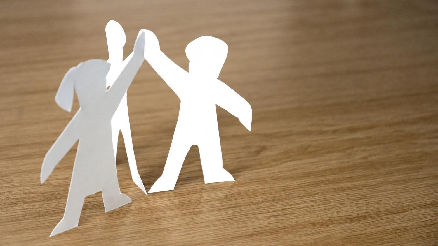 3 Pappfiguren, die sich die Hände reichen