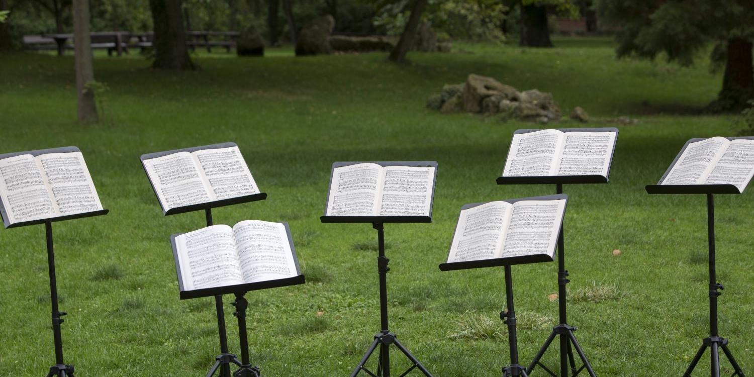 Mehrere Notenständer stehen im Park auf einer Wiese
